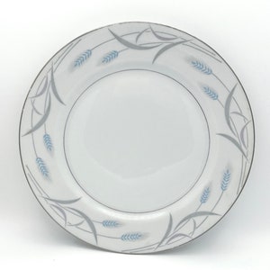 May include: A white ceramic plate with a silver rim and a blue and gray wheat design.