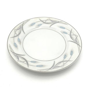 May include: A white ceramic plate with a silver rim and a blue and gray wheat design.
