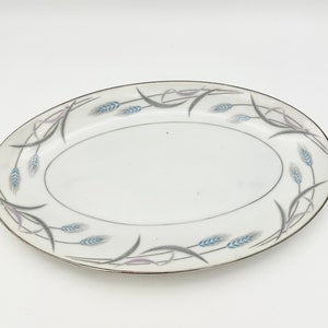 May include: White oval serving dish with a silver rim and a blue and gray wheat design.