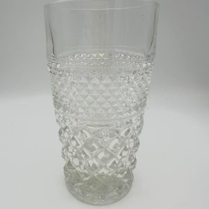 May include: A clear glass tumbler with a diamond pattern. The glass is tall and has a wide base.