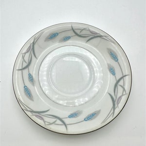 May include: A white porcelain saucer with a gold rim and a blue and gray wheat design.