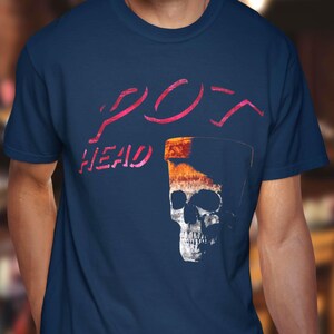 May include: Navy blue t-shirt with the words "POT HEAD" in pink script above a graphic of a skull inside a pocket. The skull is white with black shadows and details.