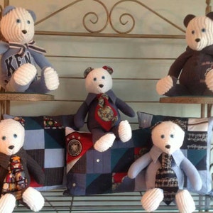 Puede incluir: Cinco osos de peluche blancos con camisas y corbatas a rayas azules y blancas. Los osos est&aacute;n sentados en un estante con almohadas de patchwork azul y blanco.