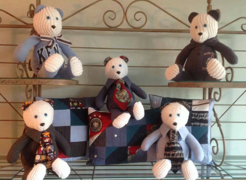 Puede incluir: Cinco osos de peluche blancos con camisas y corbatas a rayas azules y blancas. Los osos est&aacute;n sentados en un estante con almohadas de patchwork azul y blanco.