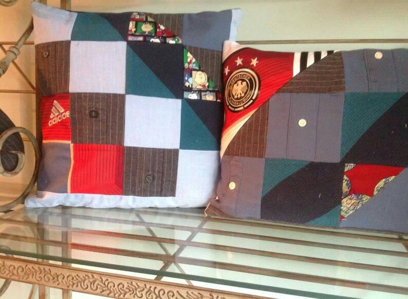 Puede incluir: Dos almohadas decorativas hechas de tela reutilizada. La almohada de la izquierda es un mosaico de tela azul, roja y gris con la palabra "adidas" impresa en ella. La almohada de la derecha es un mosaico de tela azul, roja y gris con un bal&oacute;n de f&uacute;tbol y estrellas impresas en ella.