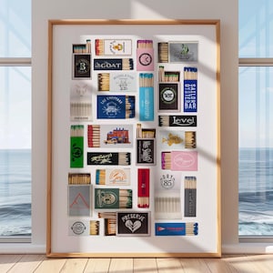 May include: A framed collage of matchbox labels featuring various designs and logos. The labels are arranged in a grid pattern and include names like "The Goat", "Dry 85", "Level", and "The Preserve".