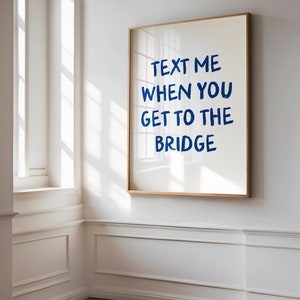 Peut inclure: Une impression encadrée avec le texte "TEXT ME WHEN YOU GET TO THE BRIDGE" en lettres bleues sur fond blanc.