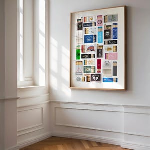 May include: A framed collage of matchbox labels, featuring a variety of designs and colors. The labels are arranged in a grid pattern, and some of them include text such as "GOAT", "PRESERVE", and "DRY 85".