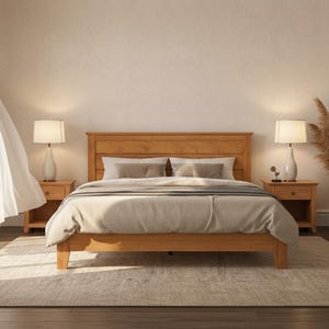 May include: A wooden bed frame with a headboard, nightstands, and lamps. The bed is made with a light-colored comforter and pillows. A rug is on the floor, and a vase with decorative plants is in the corner. The room has a neutral color palette.