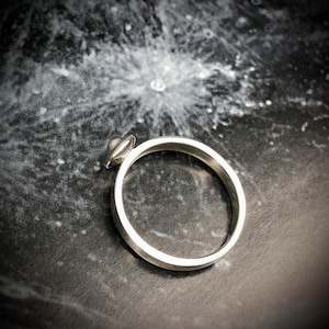 May include: A silver ring with a small, round, silver UFO-shaped design on the top.