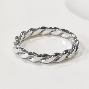 May include: A silver twisted band ring. The ring is made of a single piece of metal that is twisted to create a unique and stylish design.