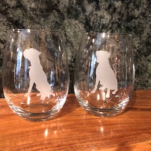 May include: Two clear glass wine glasses with etched silhouettes of dogs. The dogs are facing to the left and right.