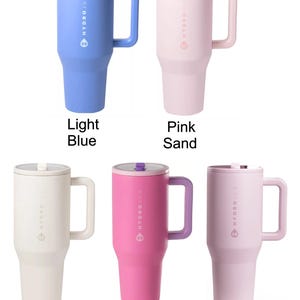 May include: A collection of insulated travel mugs in various colors, including light blue, pink, cream, and sweetpea. Each mug has a handle, a lid, and the "HYDROJUG" logo. The mugs are designed to keep beverages cold or hot.
