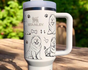 May include: A white Stanley tumbler with a handle and a straw, featuring a repeating black line art pattern of Chow Chow dogs, paw prints, and bones. The Stanley logo is printed in black near the top rim of the cylindrical insulated cup.