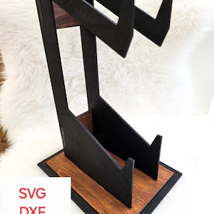 May include: A black wooden stand with two angled shelves for displaying vinyl records. The stand has a brown wood base and a black painted finish.