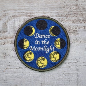 May include: A blue embroidered patch with a circle of yellow and black moons and the text "Dance in the Moonlight".