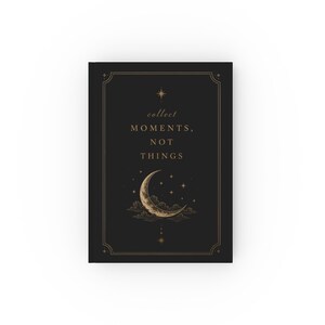 Peut inclure: Un carnet à couverture rigide noire avec le texte doré "collect MOMENTS, NOT THINGS" centré sur la couverture. Sous le texte se trouve une illustration dorée d'un croissant de lune entouré d'étoiles et de nuages.
