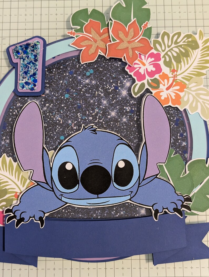 May include: A blue and purple Stitch character from the Disney movie Lilo & Stitch peeks over a blue banner with a glittery blue number one on a dark blue background with glitter. The background is decorated with green and orange tropical leaves and flowers.