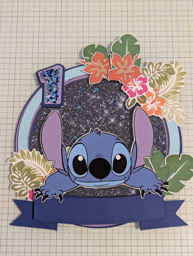 May include: A blue Stitch character from Lilo & Stitch peeks over a blue banner with a glittery, black background. The banner has a blue circle with a glittery number one in the top left corner. The background is a white grid.