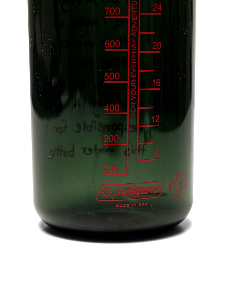 May include: A dark green Nalgene water bottle with red measurement markings and the text "FOR YOUR EVERYDAY ADVENTURE." The bottle has measurements in milliliters and ounces, and the brand name "nalgene" is visible.