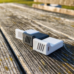 May include: Three small, rectangular devices with vents on the side. The devices are white, gray, and black.