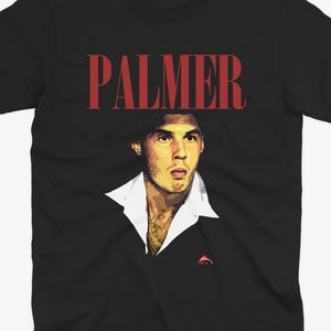 May include: Black t-shirt with a red "PALMER" text and a photo of a man with a white shirt and a gold chain.