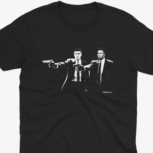 Pode incluir: Camiseta preta com uma imagem em silhueta branca de dois homens de terno segurando armas. O texto "Pulp Fiction" é impresso abaixo da imagem.