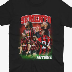 Può includere: Maglietta nera con una grafica in stile retrò del calciatore Hlompho Kekana. La grafica presenta Kekana con una maglia rossa e nera con il testo "SEMENYO ANTOINE" e "SEMENYO 24".