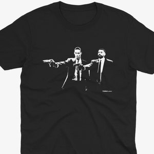 May include: Black t-shirt featuring a white silhouette of two men holding guns, one in a suit and the other in a suit and tie. The text "Pulp Fiction" is at the bottom of the image.