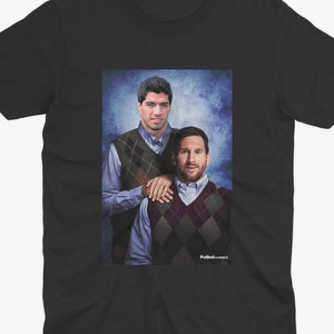 May include: Black t-shirt featuring a photograph of two men wearing sweaters. The men are standing side-by-side and smiling. The background is a blue and white gradient.