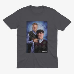 May include: A dark gray t-shirt with a photo of two men wearing sweaters. The men are standing in front of a blue and white background. The text "Fullback Classics" is printed on the bottom of the photo.