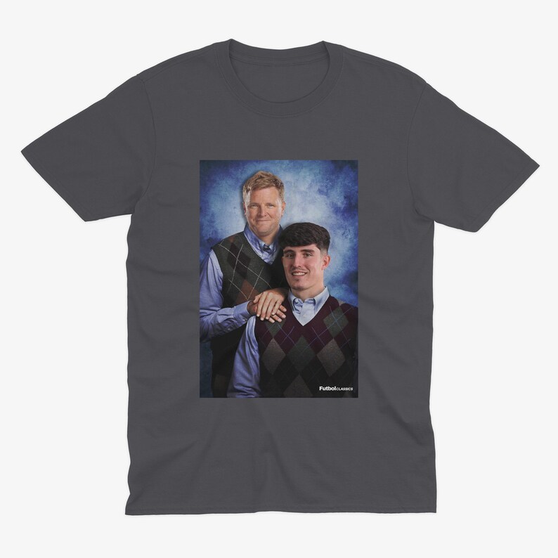 May include: A dark gray t-shirt with a photo of two men wearing sweaters. The men are standing in front of a blue and white background. The text "Fullback Classics" is printed on the bottom of the photo.