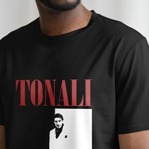 May include: Black t-shirt with a red "TONALI" graphic and a black and white image of a man in a white suit.