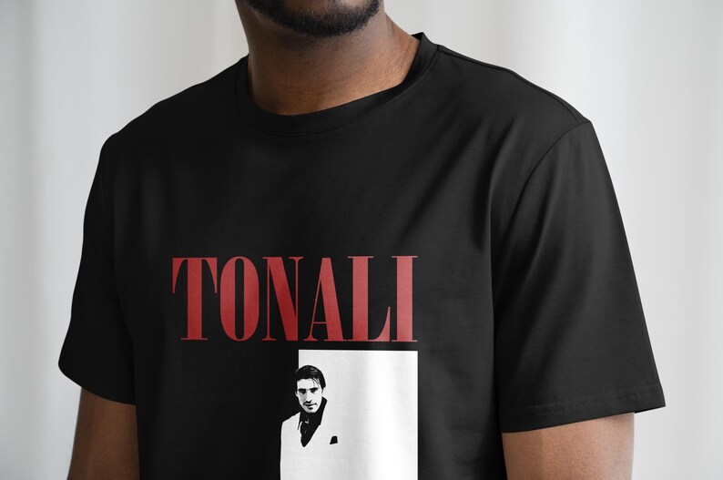 May include: Black t-shirt with a red "TONALI" graphic and a black and white image of a man in a white suit.
