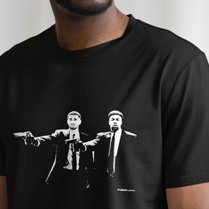 May include: Black t-shirt with a white graphic print of two men in suits holding guns. The text "Pulp Fiction" is printed at the bottom of the graphic.