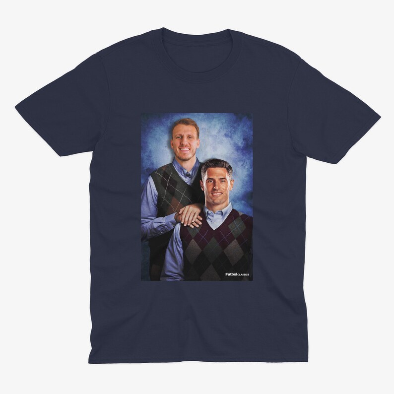 May include: A navy blue t-shirt featuring a photograph of two men wearing sweaters. The men are standing in front of a blue and white background. The text "Football Classics" is printed at the bottom of the image.