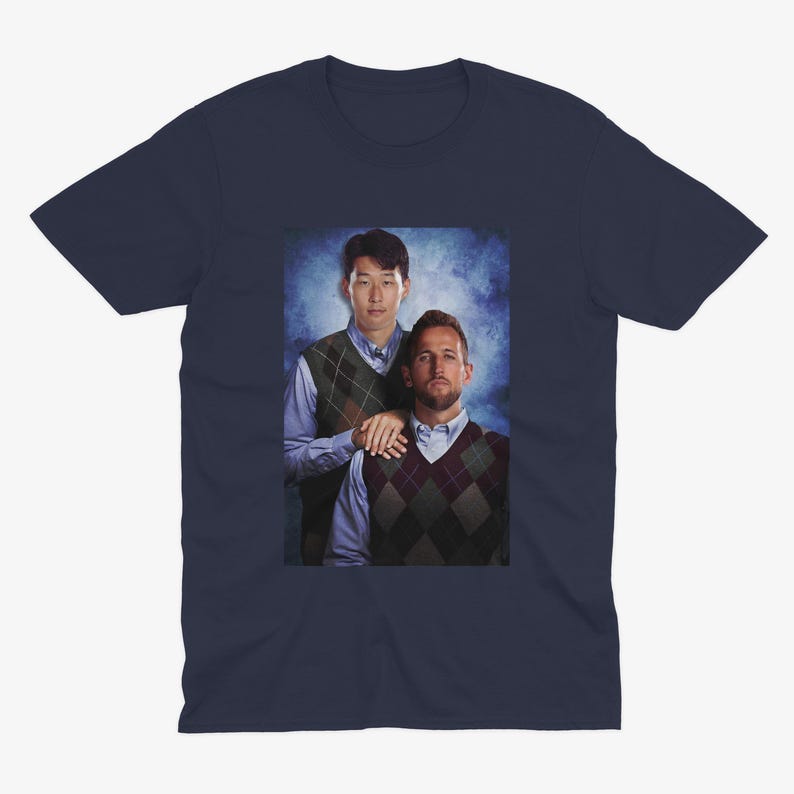 Op de afbeelding: Een marineblauw t-shirt met een foto van twee mannen die truien dragen. De man links draagt een groen-witte trui met een patroon en de man rechts draagt een bruin-witte trui met een patroon.