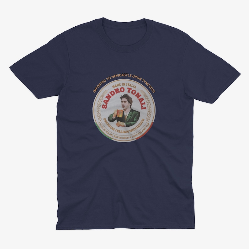 Pu&ograve; includere: Una maglietta blu navy con un'etichetta in stile vintage che presenta un'immagine di un calciatore dei cartoni animati che tiene una birra. L'etichetta recita "Sandro Tonali, Made in Italia, Centrocampista italiano di alta qualit&agrave;, Importato a Newcastle Upon Tyne 2023".