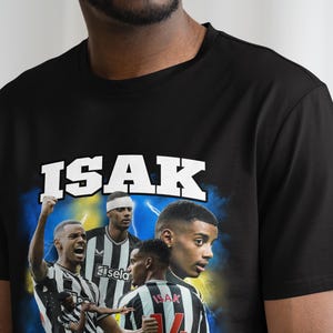 Puede incluir: Camiseta negra con un estampado gr&aacute;fico de un jugador de f&uacute;tbol, con el texto "ISAK" sobre la imagen.