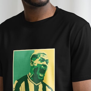 May include: Black t-shirt with a green and yellow graphic print of a man's face. The man is wearing a striped jersey.