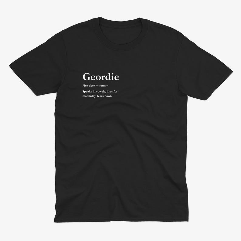 Puede incluir: Camiseta negra con la definici&oacute;n de "Geordie" impresa en blanco. La definici&oacute;n incluye la pronunciaci&oacute;n, la parte de la oraci&oacute;n y una breve descripci&oacute;n: "Speaks in vowels, lives for matchday, fears nowt."
