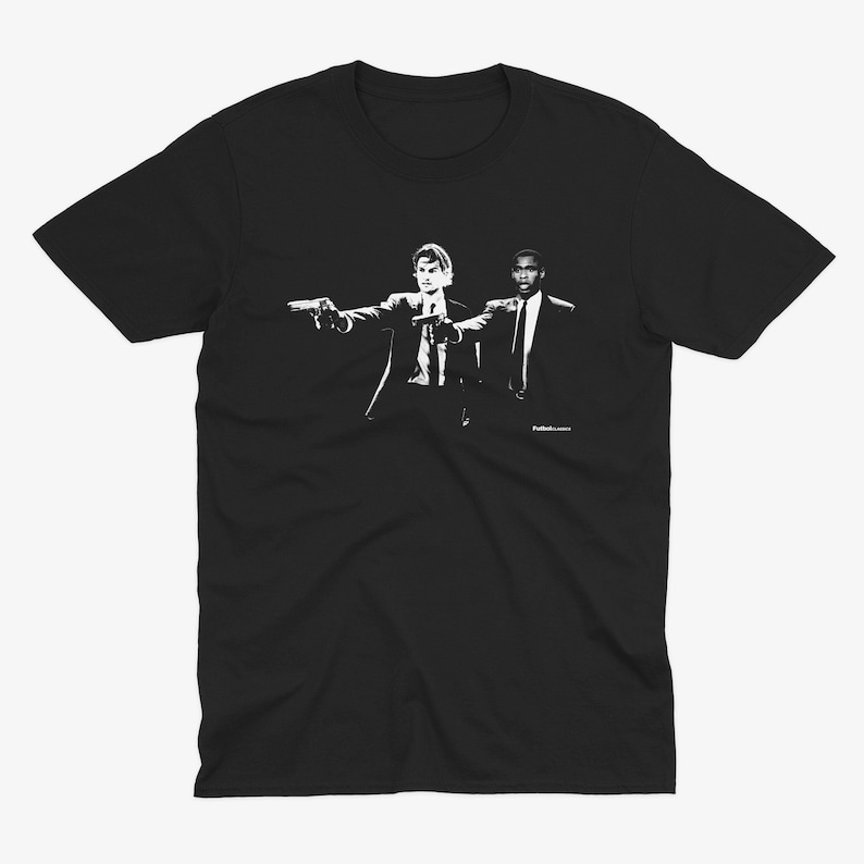 May include: Black t-shirt featuring a white silhouette of two men in suits holding guns, with the text "Pulp Fiction" at the bottom.