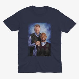 May include: A navy blue t-shirt featuring a photo of two men wearing sweaters. The men are standing next to each other and smiling. The text "Full House Classics" is printed on the bottom of the photo.