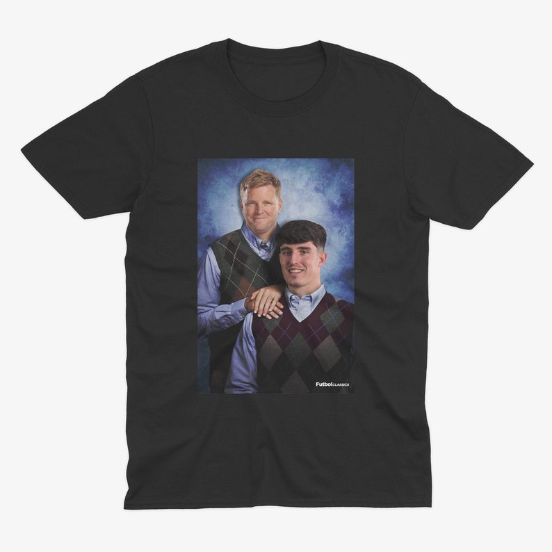 May include: Black t-shirt with a photo of two men wearing sweaters. The men are standing in front of a blue and white background. The text "Fullback Classics" is printed on the bottom of the photo.