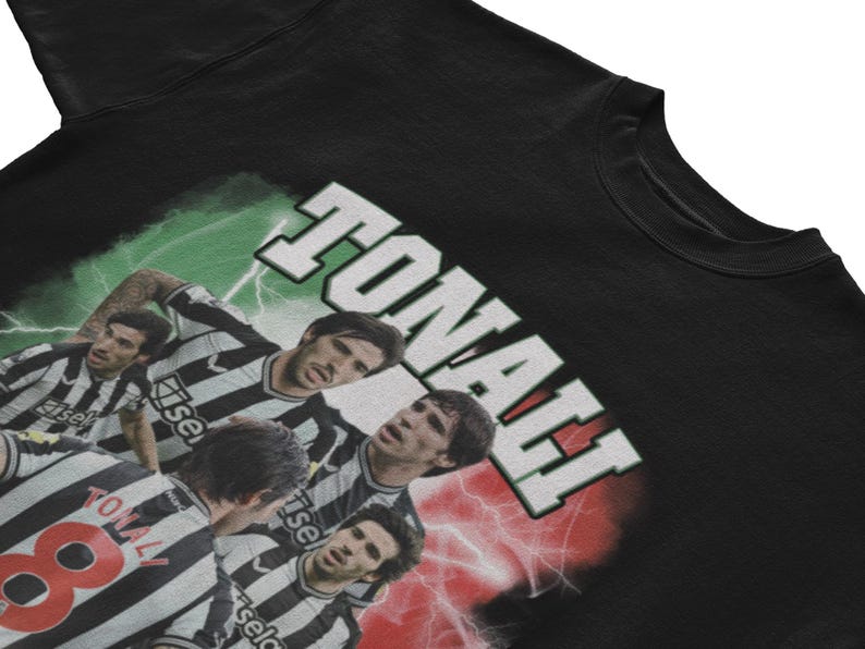 Puede incluir: Camiseta negra con un estampado gr&aacute;fico de jugadores de f&uacute;tbol que llevan camisetas a rayas blancas y negras. El texto "TONALI" est&aacute; impreso en blanco sobre un fondo verde, rojo y blanco.