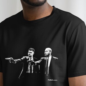 May include: Black t-shirt with a white graphic print of two men in suits holding guns. The text "FutbolClassics" is printed at the bottom of the graphic.