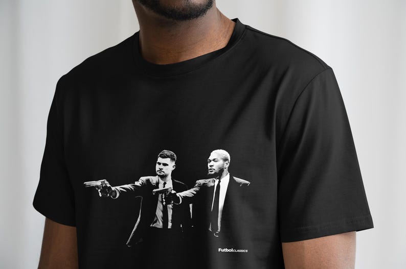 May include: Black t-shirt with a white graphic print of two men in suits holding guns. The text "FutbolClassics" is printed at the bottom of the graphic.