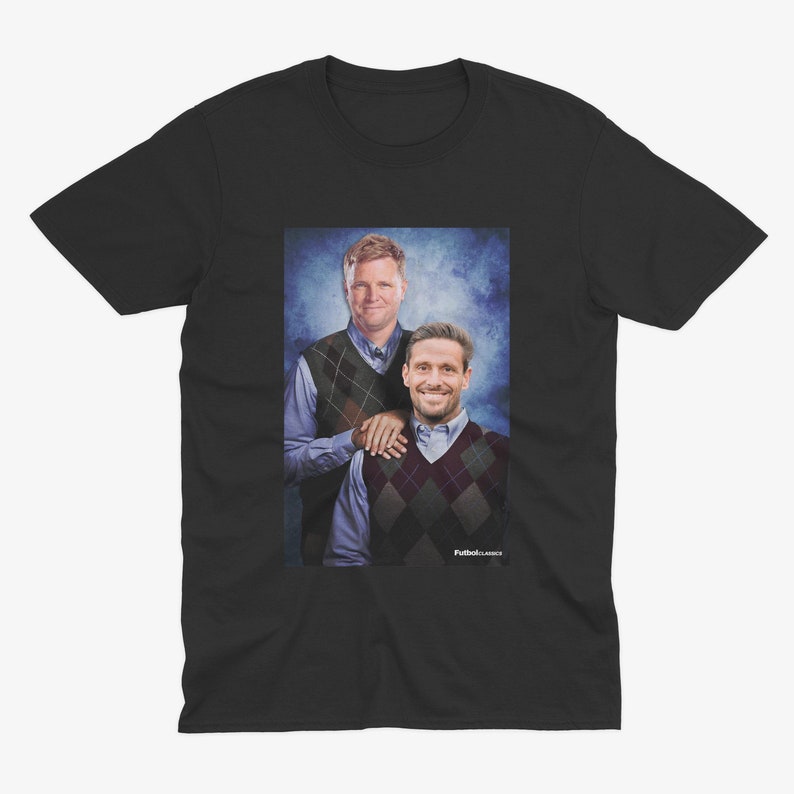 May include: A black t-shirt with a photo of two men wearing sweaters. The man on the left is wearing a blue and white patterned sweater and the man on the right is wearing a red and white patterned sweater. The men are standing in front of a blue and white background.