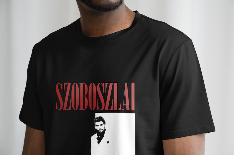 K&ouml;nnte beinhalten: Schwarzes T-Shirt mit einem roten Grafikdruck des Namens "SZOBOSZLAI" und einem Schwarzwei&szlig;foto eines Mannes im wei&szlig;en Anzug.