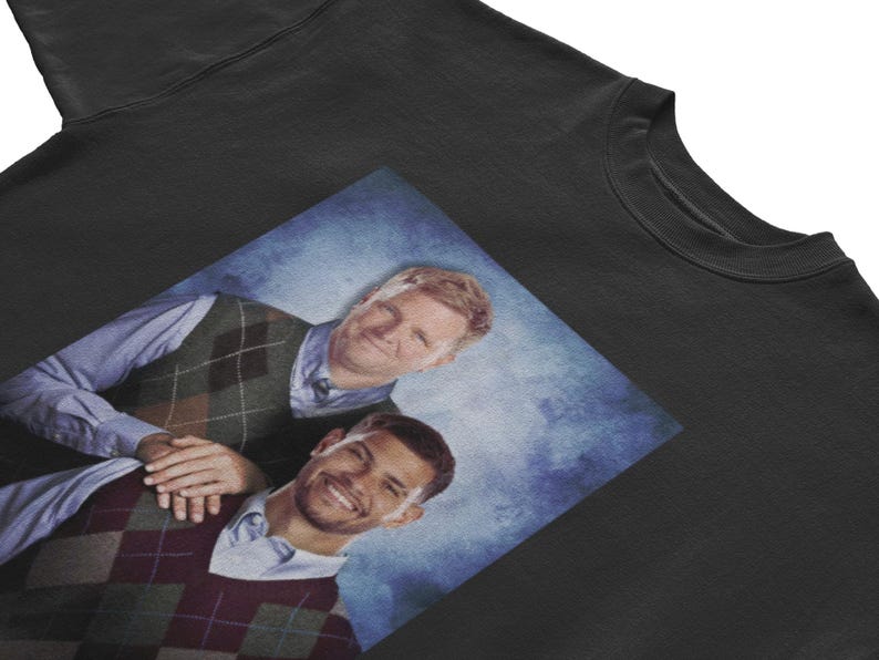 May include: Black t-shirt featuring a printed image of two people wearing argyle vests and button-down shirts. The image has a blue background. The t-shirt is made of a soft, comfortable material.